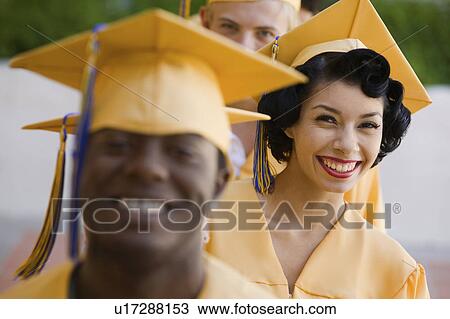 Stock Image - Graduates in line for degree outside, focus on woman. Fotosearch