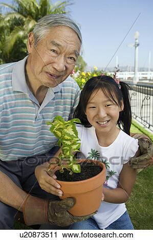 Stock Image - Grandfather and granddaughter gardening, (portrait). Fotosearch