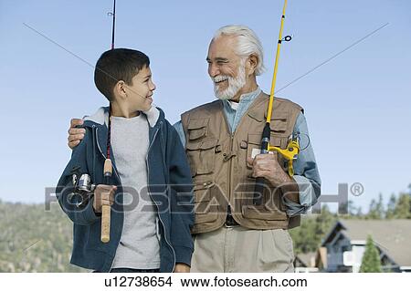 Grandfather and grandson holding fishing rods outdoors, smiling View Large Photo Image Picture - Grandfather and grandson holding fishing rods outdoors, smiling. Fotosearch