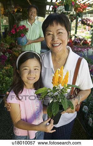 Grandmother and granddaughter in plant nursery holding flowers, portrait View Large Photo Image Stock Photo - Grandmother and granddaughter in plant nursery holding flowers, portrait. Fotosearch