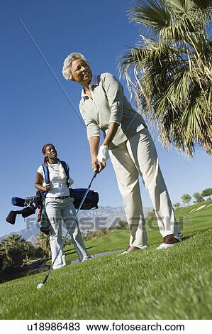Stock Image - Grandmother and granddaughter on golf course, (low angle view). Fotosearch