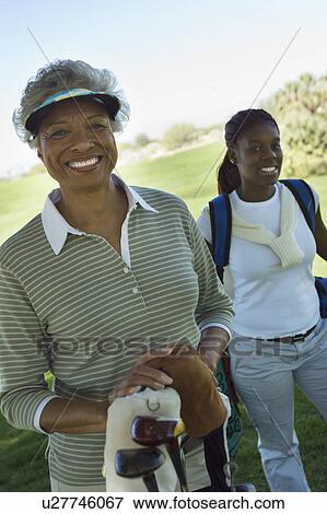 Grandmother and granddaughter on golf course, smiling, (portrait) View Large Photo Image Stock Photo - Grandmother and granddaughter on golf course, smiling, (portrait). Fotosearch