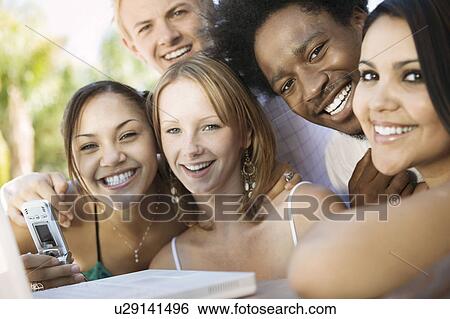 Group of friends at back yard table using laptop and cell phone, portrait, close up View Large Photo Image Stock Photograph - Group of friends at back yard table using laptop and cell phone, portrait, close up. Fotosearch