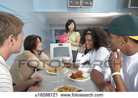 Group of friends eating at bowling alley View Large Photo Image Stock Image - Group of friends eating at bowling alley. Fotosearch