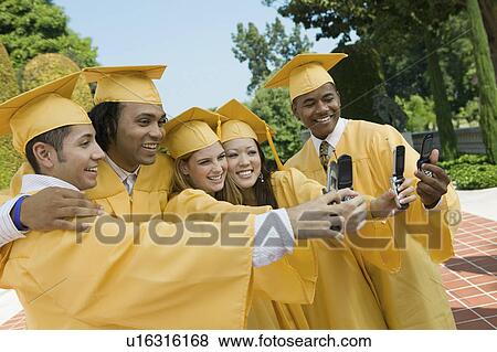 Stock Photo - Group of graduates taking pictures with cell phone outside. Fotosearch