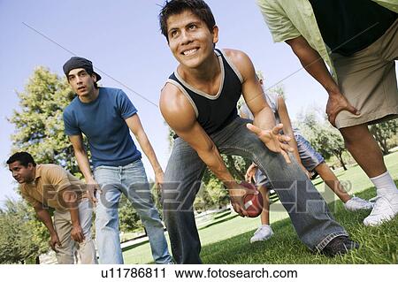 Group of men playing football in park, low angle view. View Large Photo Image Stock Image - Group of men playing football in park, low angle view.. Fotosearch