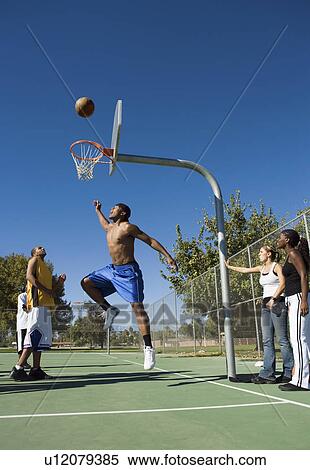 Group of young people playing basketball, one player jumping for ball View Large Photo Image Stock Photography - Group of young people playing basketball, one player jumping for ball. Fotosearch