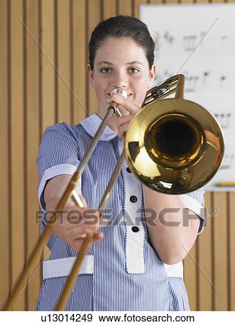 Stock Photo - High school girl playing trombone in music class, portrait. Fotosearch