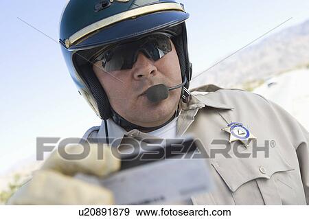 Stock Photo - Highway patrol officer examines driving license. Fotosearch