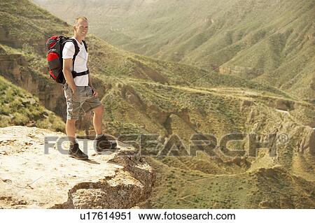 Stock Image - Hiker standing on top of mountain. Fotosearch