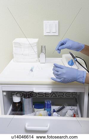 Picture - Hygienist preparing hypodermic in surgery. Fotosearch