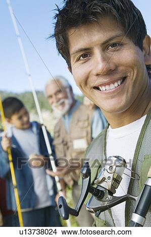 Male members of three generation family on fishing trip, focus on mid adult man, (portrait) View Large Photo Image Picture - Male members of three generation family on fishing trip, focus on mid adult man, (portrait). Fotosearch