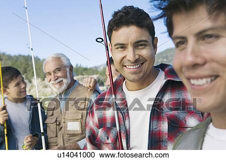 Stock Image - Male members of three generation family on fishing trip, focus on mid adult man, (portrait). Fotosearch
