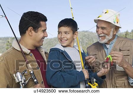 Stock Image - Male members of three generation family on fishing trip, smiling. Fotosearch