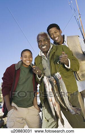 Male members of three generation family holding fishes, smiling, (portrait) View Large Photo Image Stock Image - Male members of three generation family holding fishes, smiling, (portrait). Fotosearch