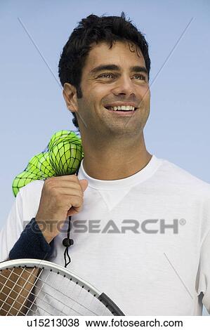 Stock Photo - Male Tennis Player holding tennis balls and racket, front view. Fotosearch