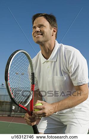 Stock Photograph - Male Tennis Player Preparing to Serve, low angle view. Fotosearch