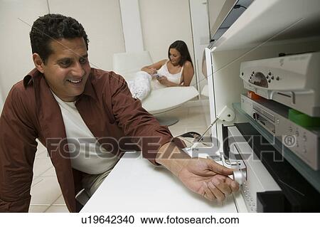 Stock Image - Man Adjusting Dial on Stereo system, close up. Fotosearch