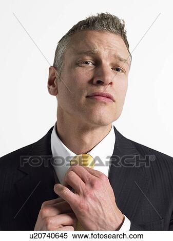 Stock Photography - Man adjusting tie in studio, head and shoulders. Fotosearch