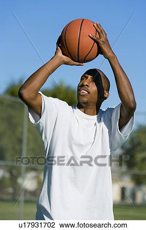 Stock Image - Man aiming to shoot basketball. Fotosearch