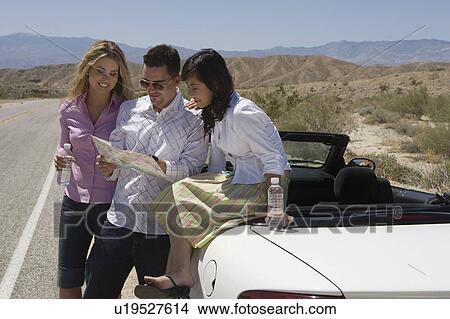 Picture - man and two women looking at map. Fotosearch