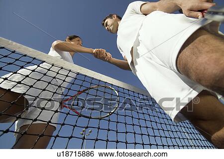 Man and woman shaking hands over tennis net on court, view from below View Large Photo Image Stock Photograph - Man and woman shaking hands over tennis net on court, view from below. Fotosearch
