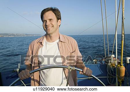 Man at helm of sailboat View Large Photo Image Stock Image - Man at helm of sailboat. Fotosearch