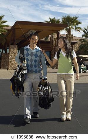 Stock Photo - Man Carrying Girlfriend's Golf Clubs outside of golf clubhouse. Fotosearch