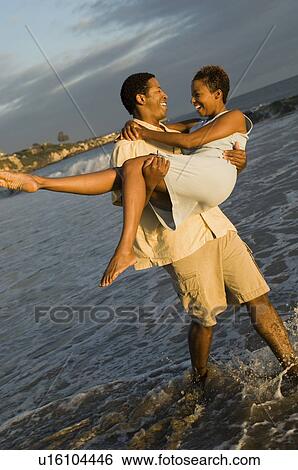 Man carrying woman at ocean View Large Photo Image Stock Photograph - Man carrying woman at ocean. Fotosearch