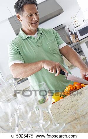 Stock Photography - Man chopping peppers in kitchen. Fotosearch