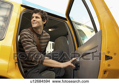 Picture - Man exiting taxi in street, low angle view. Fotosearch