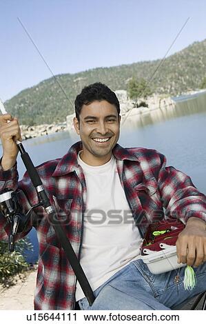 Stock Image - Man fly fishing on lake, (portrait). Fotosearch
