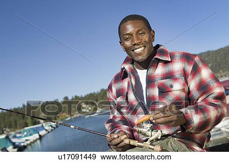 Stock Photo - Man fly fishing on lake, (portrait). Fotosearch