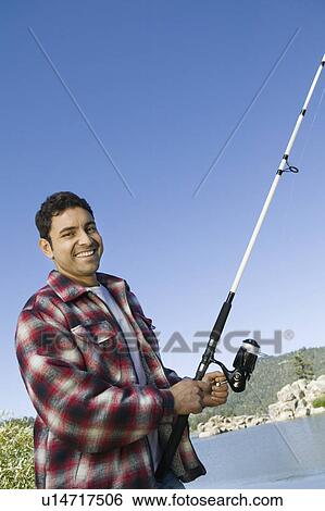 Stock Photograph - Man fly fishing on lake, (portrait). Fotosearch