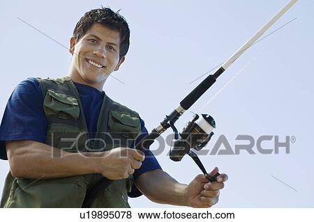 Stock Photo - Man fly fishing, (portrait), (low angle view). Fotosearch