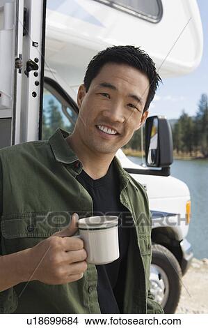 Man holding coffee mug outside of RV at lake View Large Photo Image Picture - Man holding coffee mug outside of RV at lake. Fotosearch