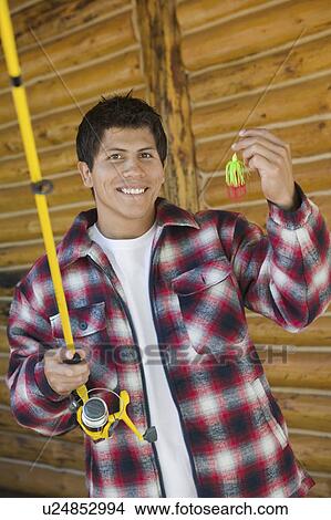 Man holding fishing rod and lure, (portrait) View Large Photo Image Picture - Man holding fishing rod and lure, (portrait). Fotosearch