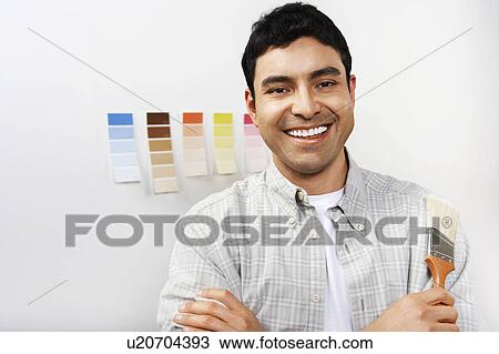 Stock Image - Man holding paintbrush, portrait. Fotosearch