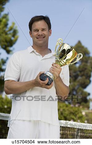 Picture - Man Holding Tennis Trophy net on tennis court, portrait. Fotosearch