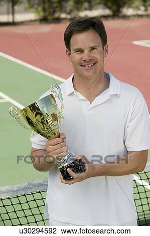 Man Holding Tennis Trophy net on tennis court, portrait View Large Photo Image Stock Image - Man Holding Tennis Trophy net on tennis court, portrait. Fotosearch