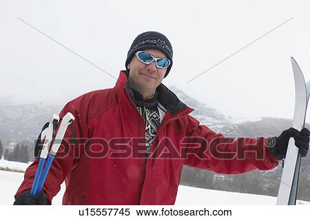 Man in winter clothing, holding skis and poles in snow View Large Photo Image Stock Photography - Man in winter clothing, holding skis and poles in snow. Fotosearch
