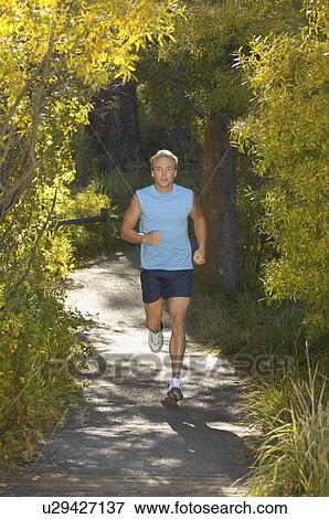 Man jogging along path in woodland View Large Photo Image Stock Photo - Man jogging along path in woodland. Fotosearch