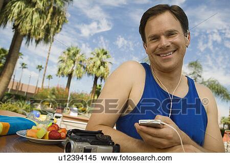 Stock Photography - Man Listening to MP3 Player outdoors, portrait.. Fotosearch