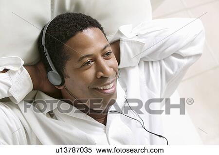 Man lying on sofa Listening to Music on portable CD player, close up, overhead view View Large Photo Image Stock Photography - Man lying on sofa Listening to Music on portable CD player, close up, overhead view. Fotosearch