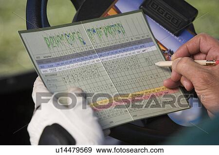 Stock Photo - Man marking score on score card, close-up of hands. Fotosearch