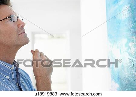 Stock Image - Man observing painting in art gallery. Fotosearch