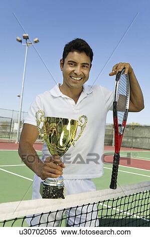 Stock Photography - Man on tennis court Holding Trophy, portrait. Fotosearch