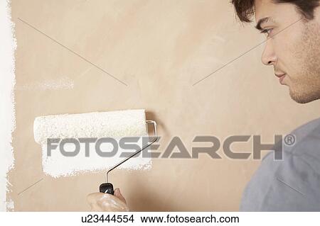 Picture - Man painting wall with paint roller, indoors, close up. Fotosearch