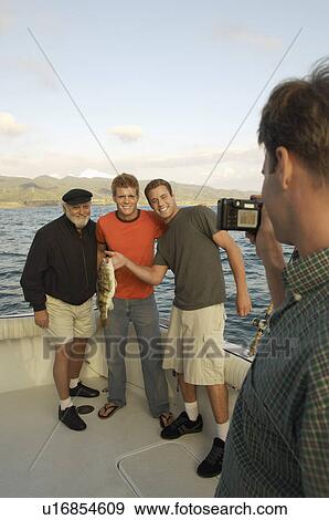 Man photographing family with fish on boat View Large Photo Image Stock Photo - Man photographing family with fish on boat. Fotosearch