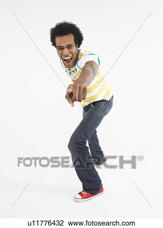 Stock Image - Man pointing in studio, full length. Fotosearch